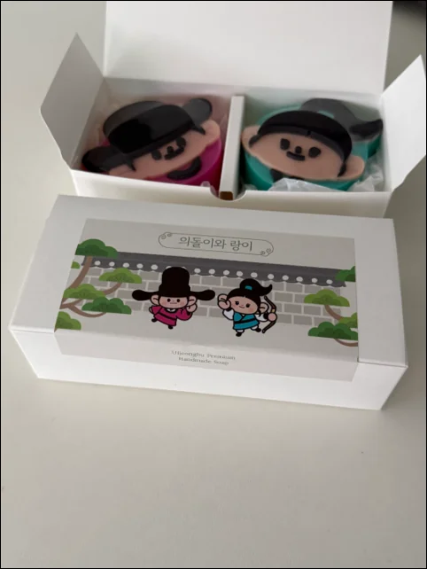 의돌이와 랑이 캐릭터 얼굴 모양 수제 비누 두 개가 들어 있는 흰색 선물 상자